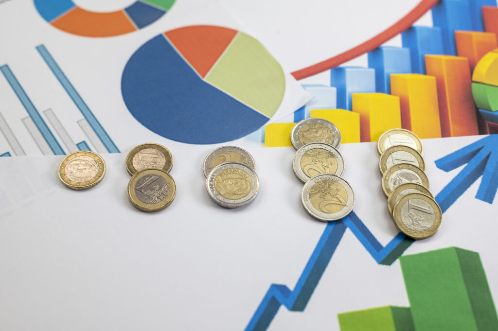 Ujęcie z wysokiego kąta monet euro i statystyki na wykresie na białym stole