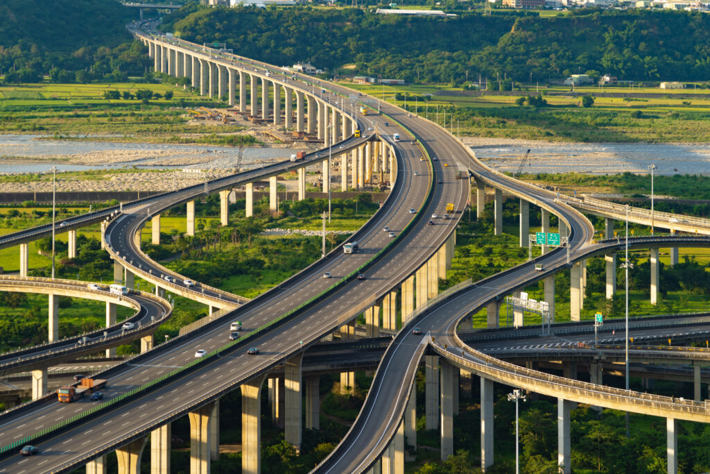 Widok z lotu ptaka na samochody jadące po złożonej autostradzie lub autostradzie z drzewami. Drogi mostowe lub ulice w strukturze architektury i koncepcji transportu. Widok z góry. Miasto miejskie, Taichung o zachodzie słońca, Tajwan.