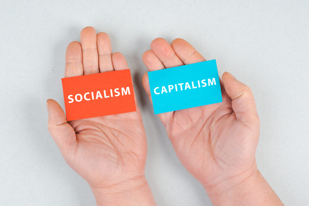 Słowa socjalizm i kapitalizm stoją na kawałkach papieru, ręce trzymają wiadomość, kwestię polityczną