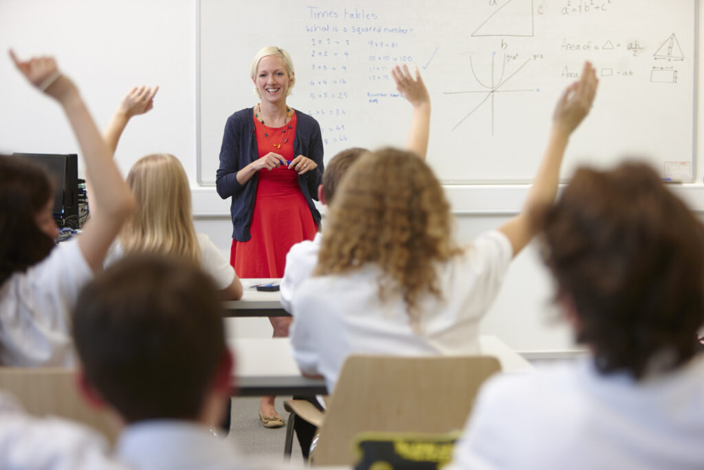 Nauczycielka i klasa z podniesionymi rękami