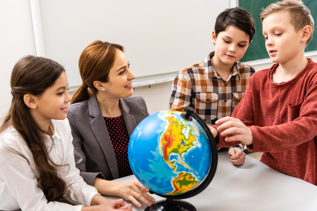 Nauczyciel i uczniowie patrzący na globus podczas nauki geografii w klasie